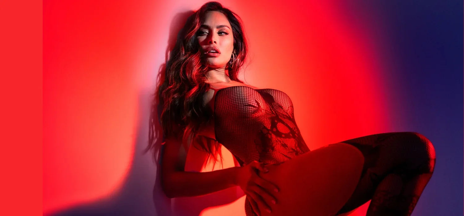 Femme portant un body résille noir élégant, lumière rouge et ambiance glamour.